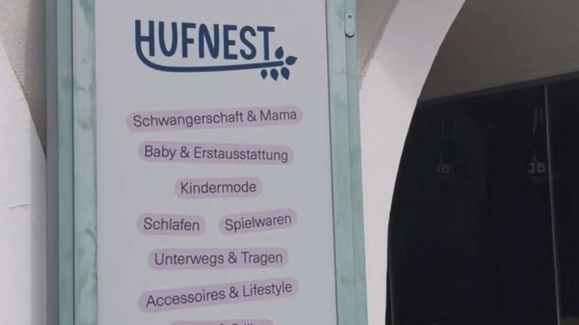 Ein Schild mit dem Namen "HUFNEST" und verschiedenen Angeboten für Babys und Kinder. Es sind auch Dienstleistungen wie Pflege und Styling aufgeführt. | © Hufnest
