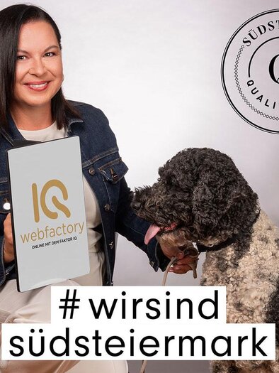 Eine Frau hält ein Schild mit der Aufschrift „IQ webfactory“ und sitzt neben einem Hund. Im Hintergrund ist das Logo „Südsteiermark Qualität“ sichtbar. | © (C) Qualtität Südststeiermark