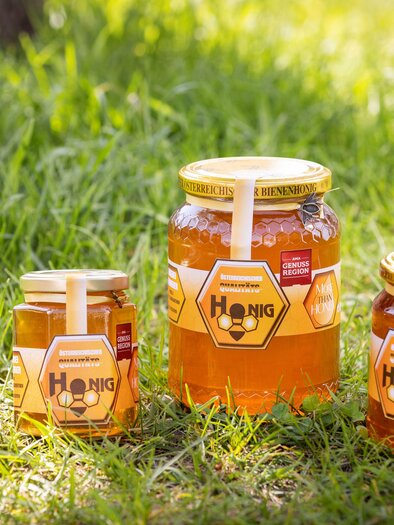 Five jars of honey are standing on green grass. The jars come in different sizes and are labeled. | © Imkerei Lemmerer