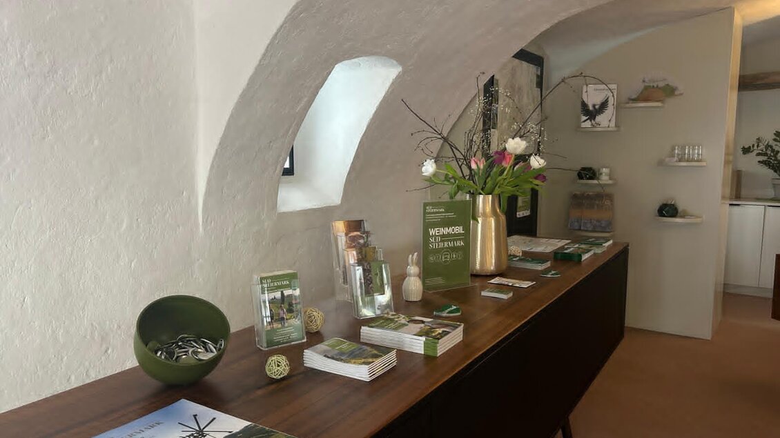 Ein einladender Empfangsbereich mit einem langen Tisch voller Prospekte und Dekor. Frische Blumen in einer Vase schaffen eine angenehme Atmosphäre. | © TV Südsteiermark