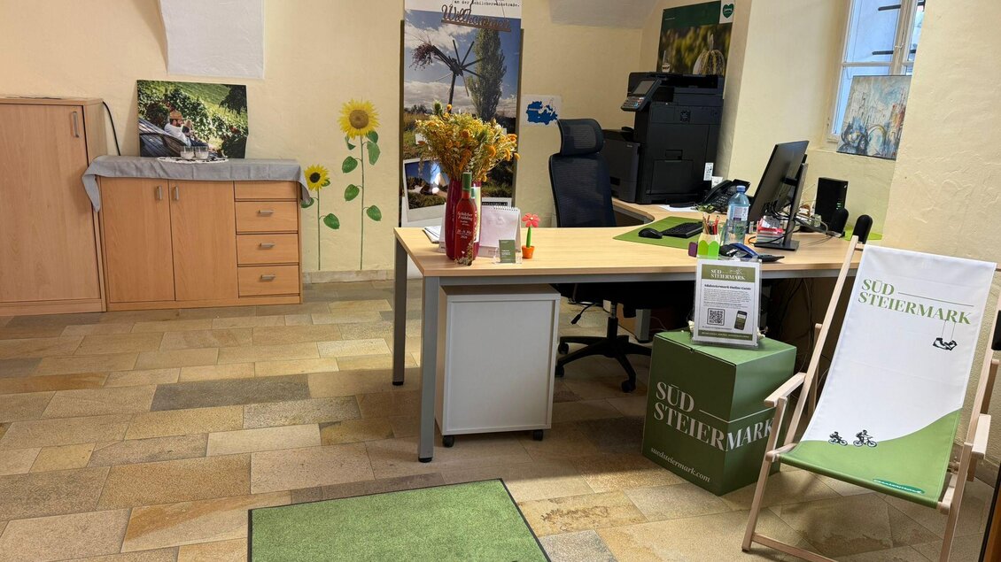Ein helles Büro mit einem Schreibtisch und einem Computer. Auf dem Boden liegt ein grüner Teppich mit dem Schriftzug „Südsteiermark“. | © TVB Südsteiermark