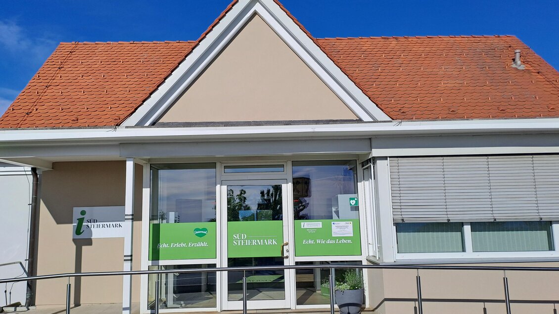 Ein modernes Bürogebäude mit einem roten Ziegeldach. Die große Glasfassade zeigt Beschilderungen und einladende Fenster. | © TV Südsteiermark