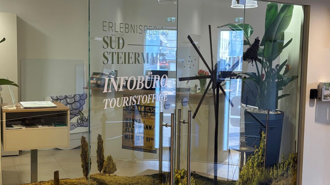 Ein modernes Tourist-Infobüro mit großen Glasscheiben. Im Hintergrund sind Weinreben und Pflanzen zu sehen. | © TV Südsteiermark
