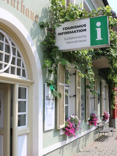 A building with signs for tourist information. The facade is decorated with plants and flowers. | © TV Südsteiermark