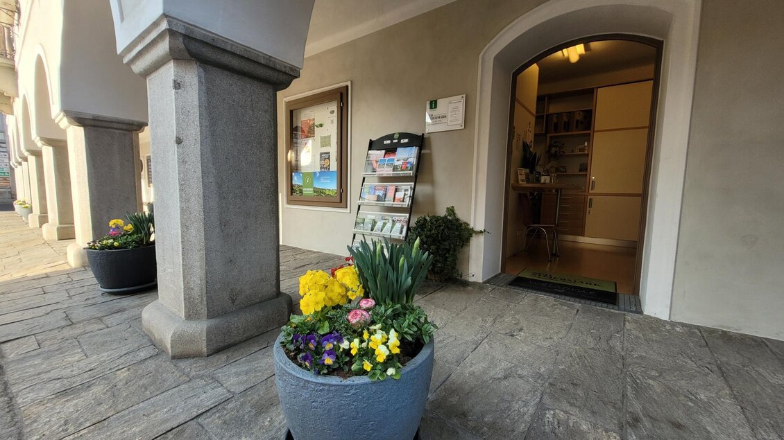 Ein Eingangsbereich mit einem Blumenkübel voller bunter Blumen. Im Hintergrund ist eine Tür zu einem Raum sichtbar. | © TV Südsteiermark - Irene Löschnig