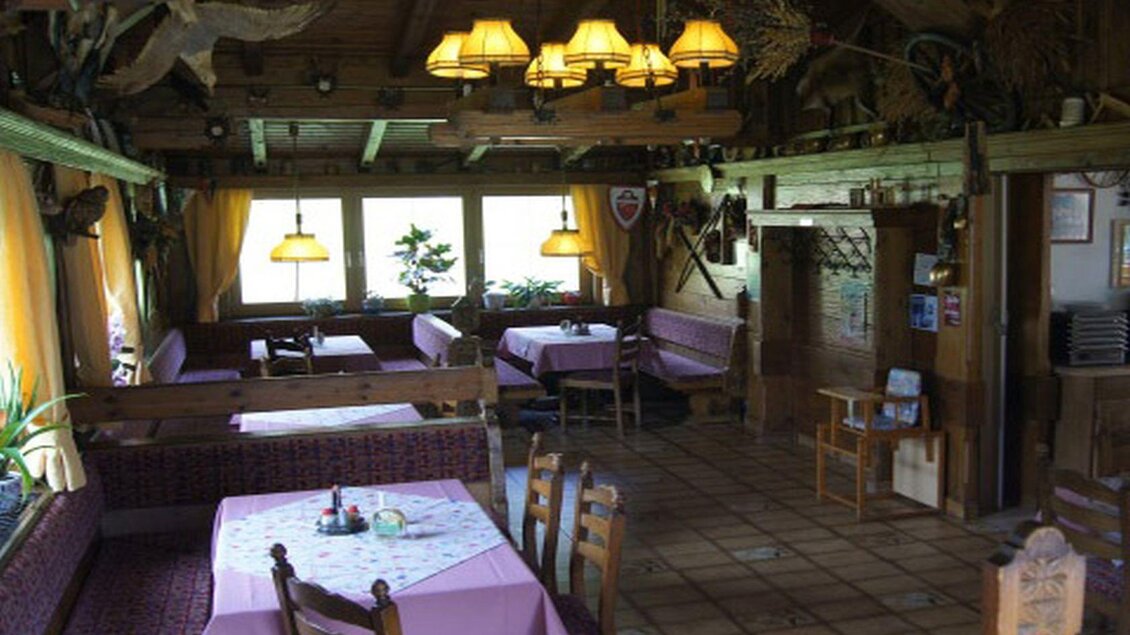 Ein gemütliches Restaurant mit Holzmöbeln und lila Tischdecken. Das Licht ist warm und die Fenster bieten einen Blick ins Grüne. | © Jägerstüberl Maissl