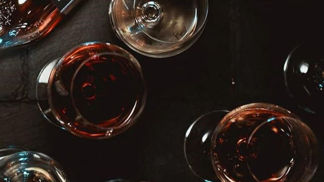 Eine Übersicht von Weingläsern mit roséfarbenem Wein auf einem dunklen Tisch. Im Hintergrund ist eine Flasche Wein sichtbar. | © Jöbstl Stammhaus