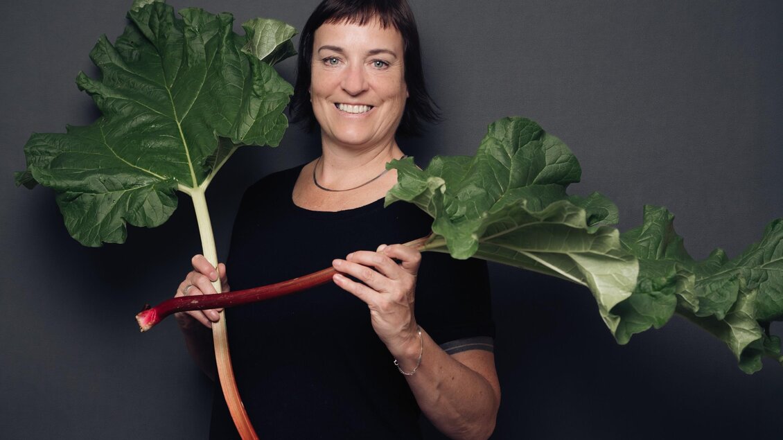Andrea Possanner hält zwei Stangen frischen Rhabarber mit großen grünen Blättern in den Händen. | © Bernd Grosseck