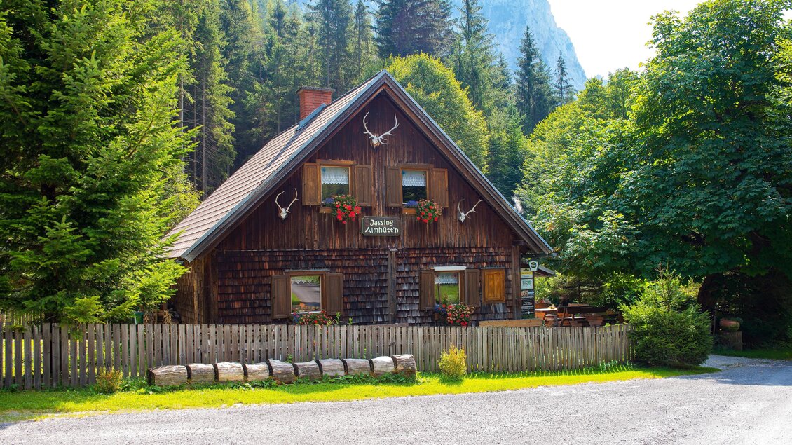 Ein gemütliches Holzhaus umgeben von Bäumen und Bergen. Die blühenden Fensterkästen verleihen dem Bild eine einladende Atmosphäre. | © TV Erzberg Leoben