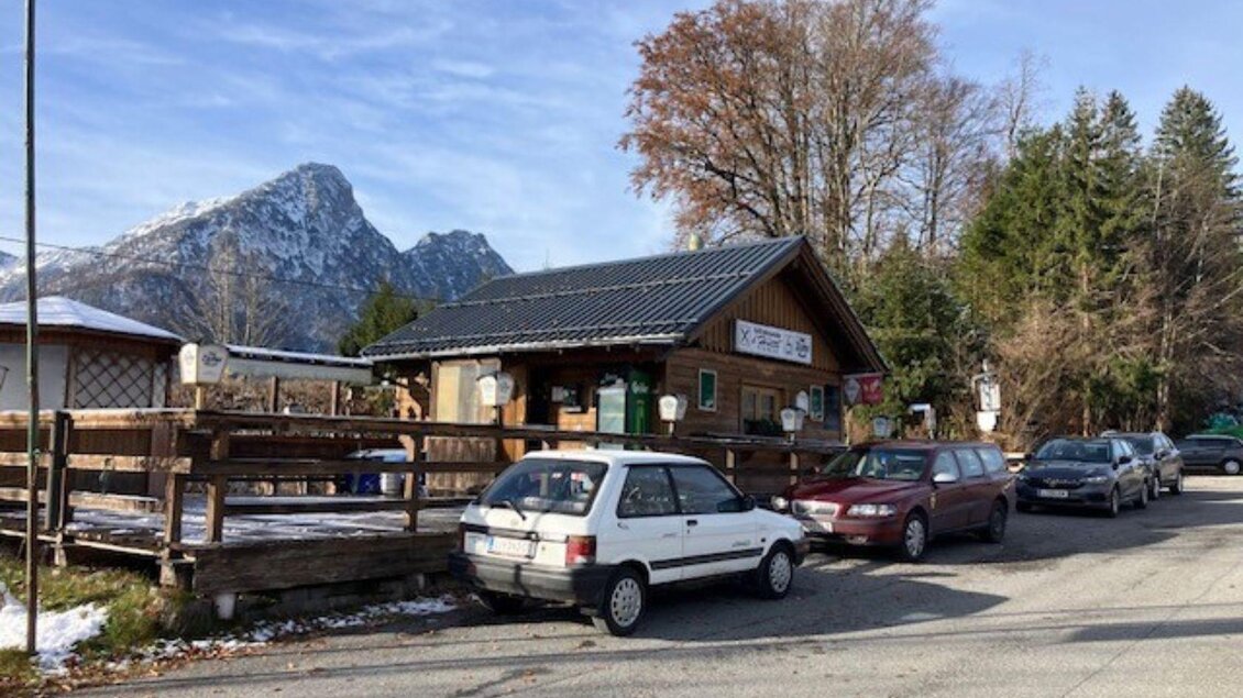 <p>Die Jausenstation s'Hüttl am Straßenrand in Bad Aussee, umgeben von Bäumen und Bergen. Mehrere Autos parken vor dem Gebäude.</p> | © TVB Ausseerland Salzkammergut