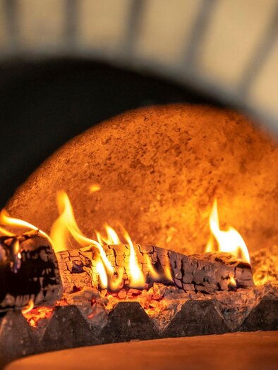 Ein offener Kamin mit loderndem Feuer und brennendem Holz. Die warme Atmosphäre erzeugt ein einladendes Ambiente. | © TV Region Graz - Lunghammer.j