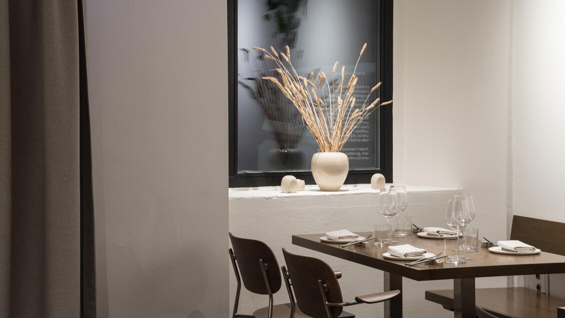 Modernes Restaurantinterieur im Kabuff Graz mit gedeckten Tischen, Stühlen und Blick durch Fenster in ruhiger Atmosphäre. | © Kabuff