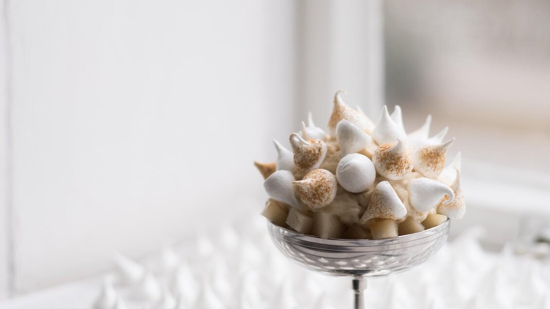 Eine elegante Dessertpräsentation mit kleinen Meringue-Häufchen und einer Schale voller dekorierter Meringues. Die Szene ist hell und freundlich, ideal für eine süße Leckerei. | © Kabuff