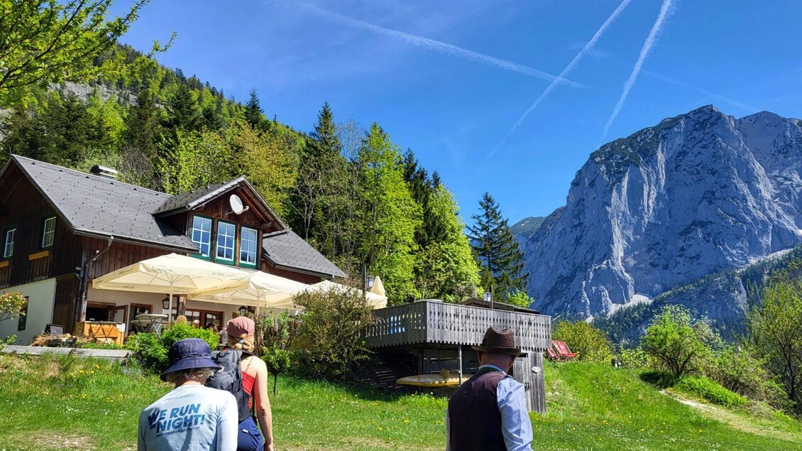 Die Jausenstation Kahlseneck direkt am Altausseer See mit der Trisselwand im Hintergrund. Große Sonnenschirme stehen auf der gemütlichen Terrasse. | © Petra Kirchschlager