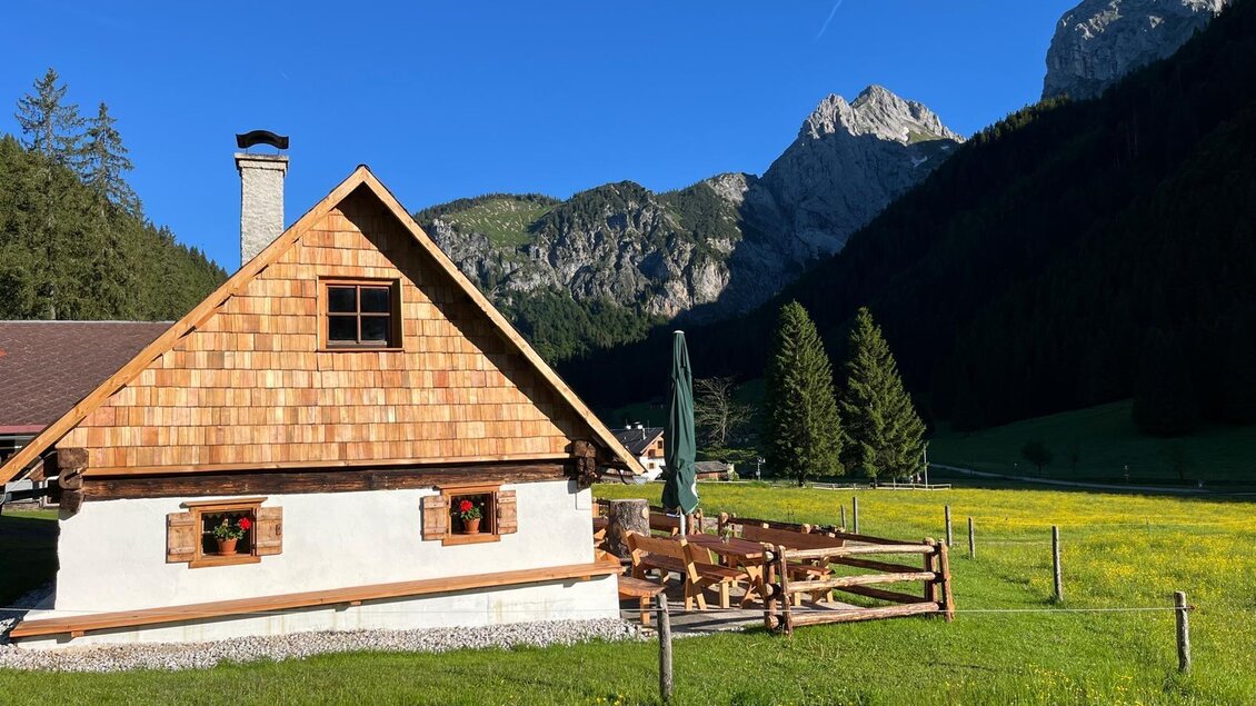 Ein gemütliches Holzhaus in einer malerischen Berglandschaft. Umgeben von Wiesen und Bergen bietet es eine idyllische Atmosphäre. | © Kainrath