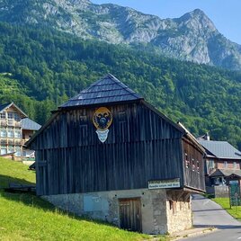 <p>Ein traditionelles Holzhaus steht in einer malerischen Landschaft. Dieses ist der Kaiserliche Stall am Ortsanfang von Grundlsee. Im Hintergrund erheben sich die majestätischen Berge von Grundlsee und grüne Wiesen.</p> | © TVB Ausseerland Salzkammergut/Bettina Scheck