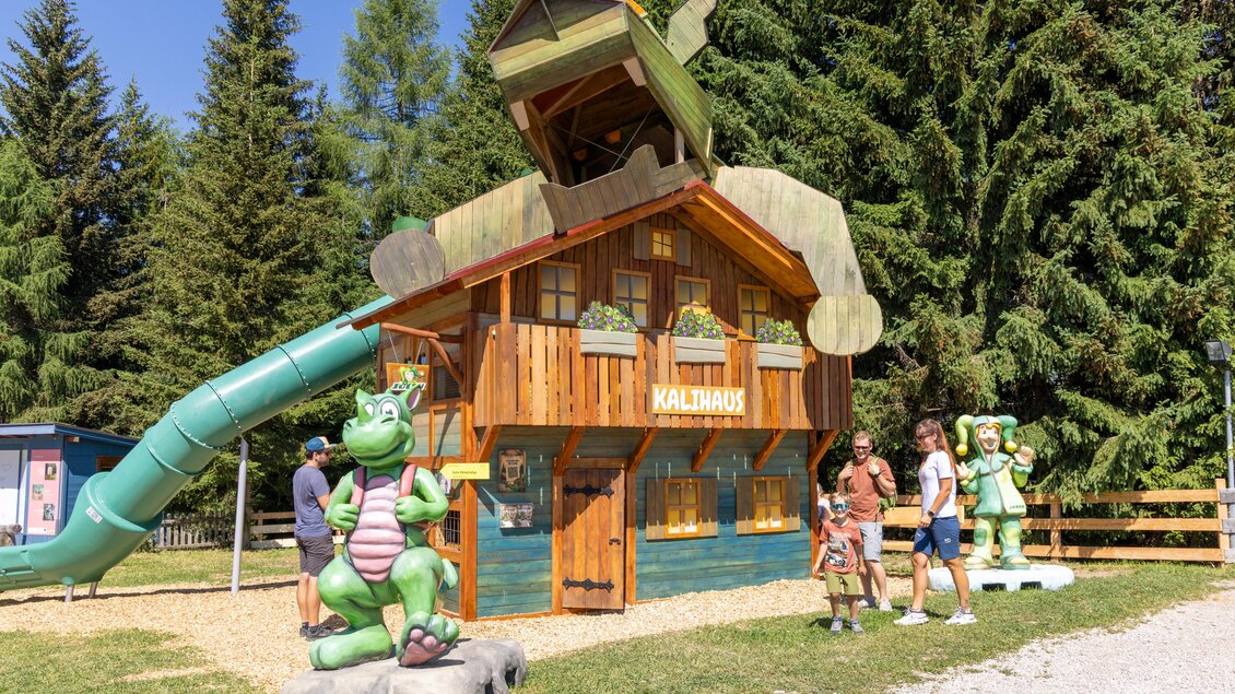 Ein buntes Spielhaus mit einer Rutsche und einem Flugzeug auf dem Dach. Kinder spielen davor, umgeben von Bäumen und einer freundlichen Atmosphäre. | © Rittisberg