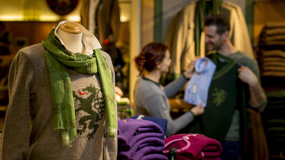 Eine elegante Modeboutique mit verschiedenen Pullovern und Schals. Ein Paar betrachtet Kleidung und berät sich freundlich. | © TV Hochsteiermark, Tom Lamm