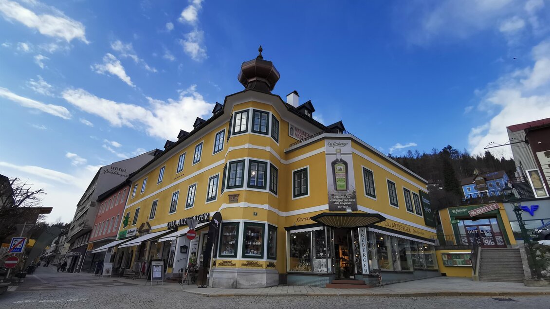 Ein buntes Gebäude mit einer charakteristischen Kuppel steht an einer Straßenkreuzung. Der Himmel ist blau mit einigen Wolken.