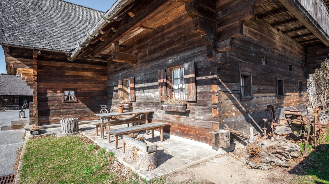 Historisches Holzgebäude des Kern Buam Museums mit Holzbänken, kleinen Fenstern und bäuerlichen Geräten in Voitsberg | © DieAbbilderei
