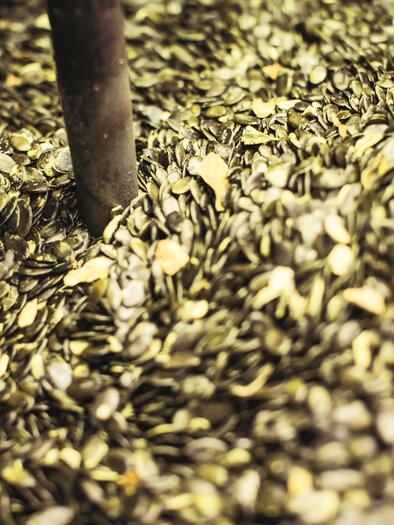 A pile of pumpkin seeds that are green and shiny. The seeds are closely packed together, creating a rustic atmosphere. | © Lupi Spuma