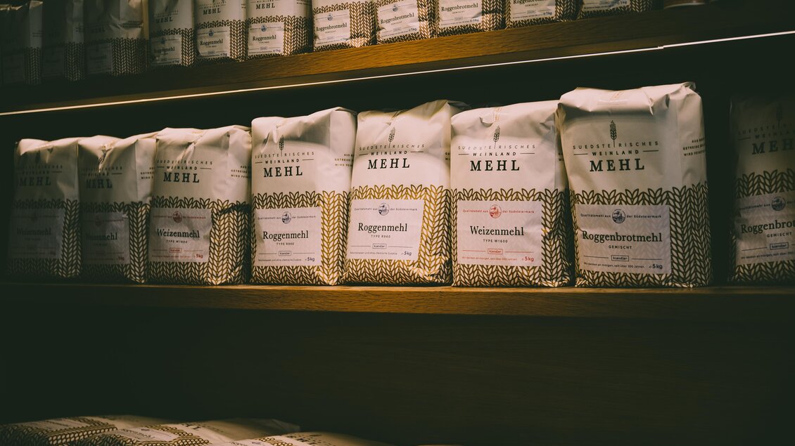 Tüten mit verschiedenen Mehlsorten stehen in Regalen. Die Verpackungen sind beschriftet und in einem warmen Licht präsentiert. | © RM SW GmbH | webquartier.at
