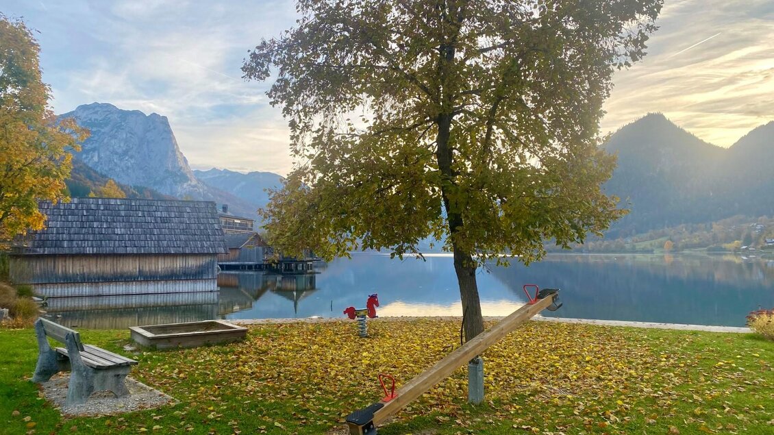 Direkt am Ufer des Grundlsees ist ein kleiner Spielplatz für die kleinen Gäste. Im Herbst sind die Blätter der Bäume Gelb, Orange oder auch Rot gefärbt und verleihen der Landschaft eine warme Atmosphäre. | © Bettina Scheck