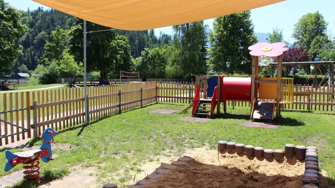 Ein schöner Spielplatz mit Rutsche, Schaukel und Sandkasten. Die Umgebung ist grün und sonnig, ideal für Kinder zum Spielen. | © Viola Lechner