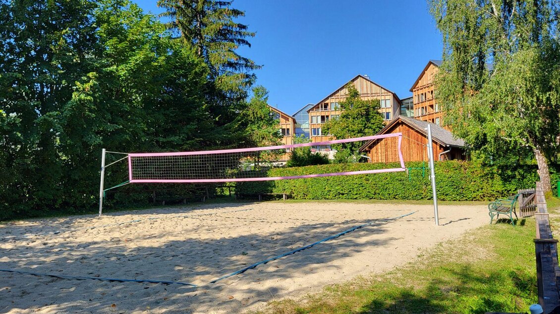 Ein Sandvolleyballplatz umgeben von Bäumen und hohen Gebäuden. Der Himmel ist klar und blau. | © Petra Kirchschlager