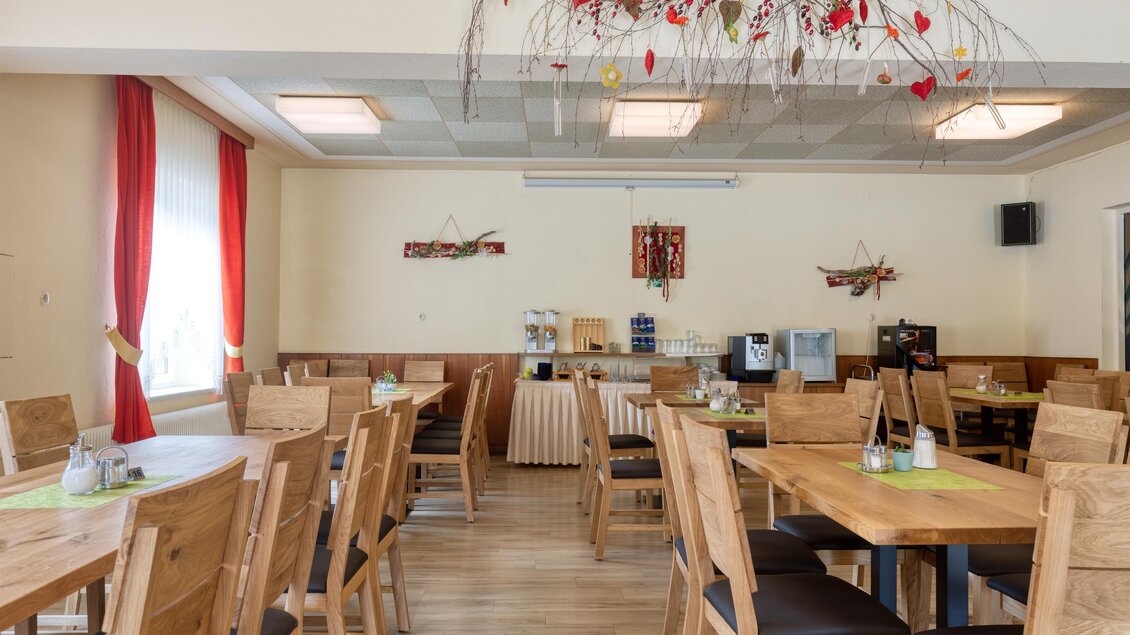 Ein helles Restaurant mit Holzstühlen und -tischen. Die Wände sind in neutralen Farben gehalten, und es gibt dekorative Elemente an der Decke. | © Gasthof Durlacher