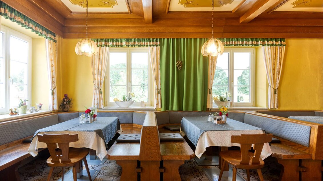 Ein gemütliches Restaurant mit holzgetäfelten Wänden und großen Fenstern. Die Tische sind mit weißen Tischdecken und Blumen dekoriert. | © Gasthof Durlacher