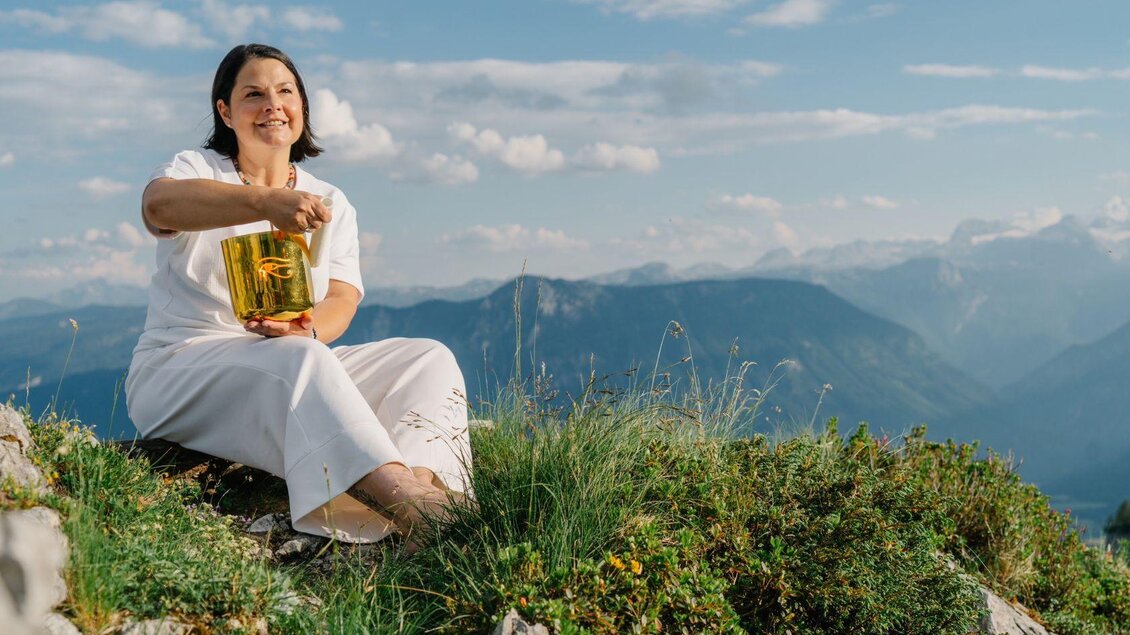 <p><p>Stephanie Bor von Klangharmonie sitzt auf einer grünen Wiese am Loser und hält eine Klangschale in ihren Händen. Im Hintergrund ist die majestätische Berglandschaft des Ausseerlandes und ein blauer Himmel zu sehen.</p></p> | © Lebensbilder, www.deine-lebensbilder.at/impressum/