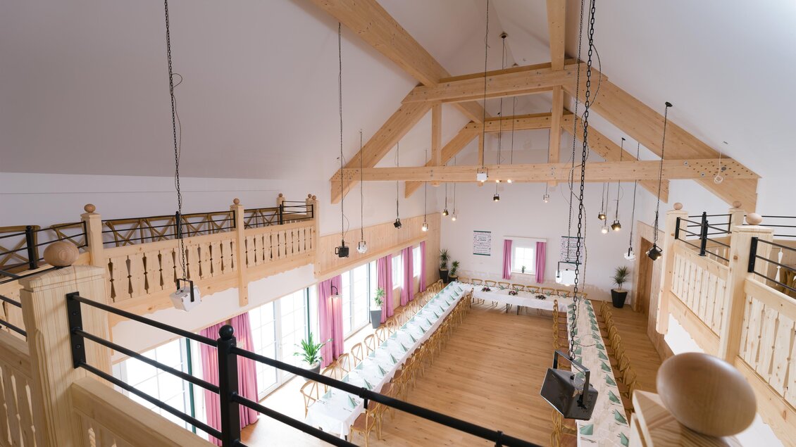 Ein großer, heller Raum mit Holzbalken und eleganter Einrichtung. Langer Tisch mit Stühlen steht bereit für eine Veranstaltung. | © www.zloam.at