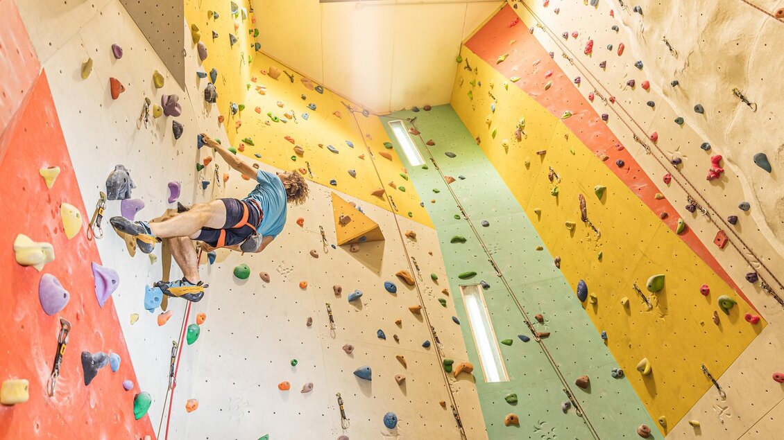 Ein Kletterer, der an einer bunten Kletterwand trainiert. Die Wand ist mit verschiedenen Griffen in verschiedenen Farben ausgestattet. | © Thomas Sattler