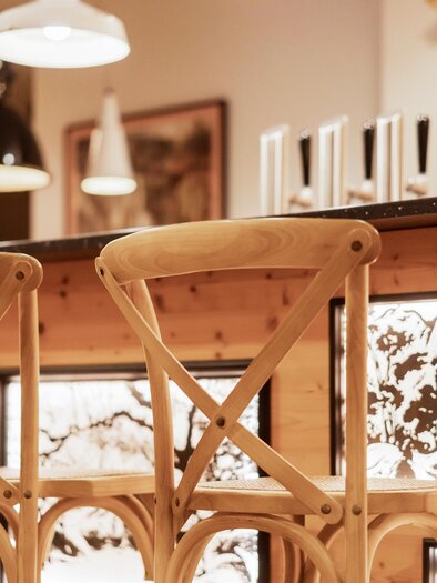 A stylish bar with wooden chairs and bright lighting. The counter showcases a modern and inviting atmosphere. | © www.zloam.at
