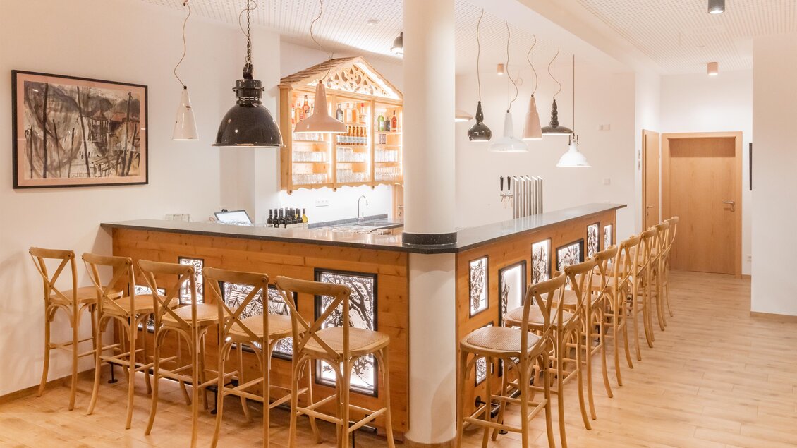 Eine moderne Bar mit Holzregalen und einer eleganten Theke. Der Raum ist hell erleuchtet und freundlich gestaltet. | © www.zloam.at