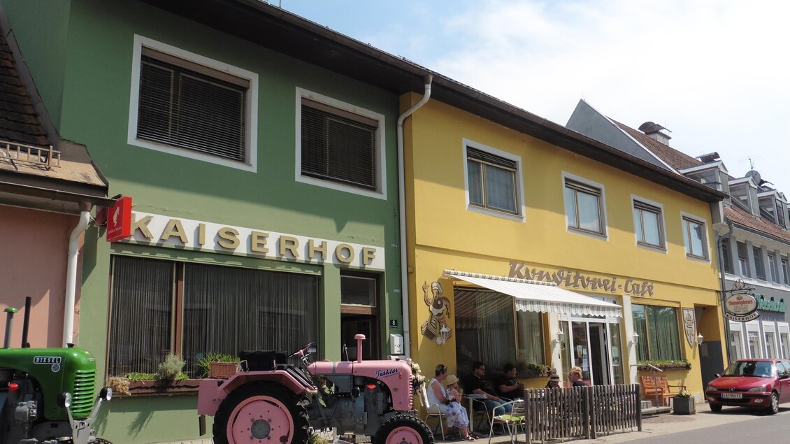Ein buntes Gebäude mit der Aufschrift "Kaiserhof" und einem Café. Vor dem Gebäude stehen zwei alte Traktoren. | © Helmut Kaiser