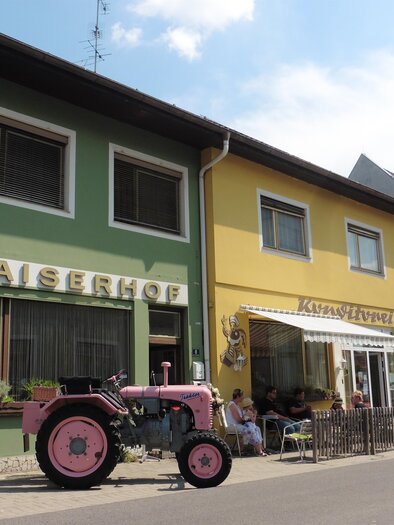 Ein buntes Gebäude mit der Aufschrift "Kaiserhof" und einem Café. Vor dem Gebäude stehen zwei alte Traktoren. | © Helmut Kaiser