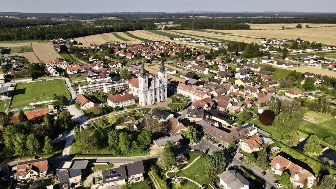 Eine Ansicht eines ruhigen Dorfes mit historischen Gebäuden und umgebenden Feldern. Die Landschaft ist grün und bietet eine idyllische Umgebung. | © Helmut Kaiser