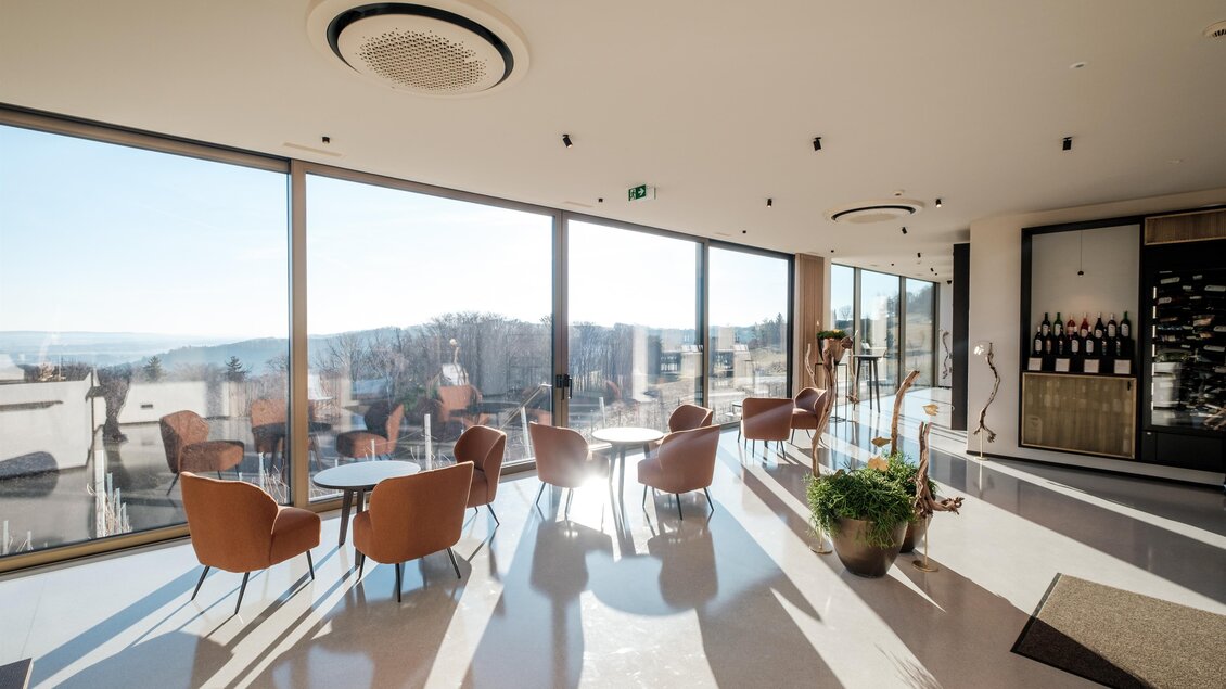 <p>Ein modernes Foyer mit großen Fenstern und einem herrlichen Ausblick. Gemütliche Stühle und Tische laden zum Verweilen ein. Kowald VINO.TAKE in Bad Loipersdorf.</p> | © Der M-Effekt