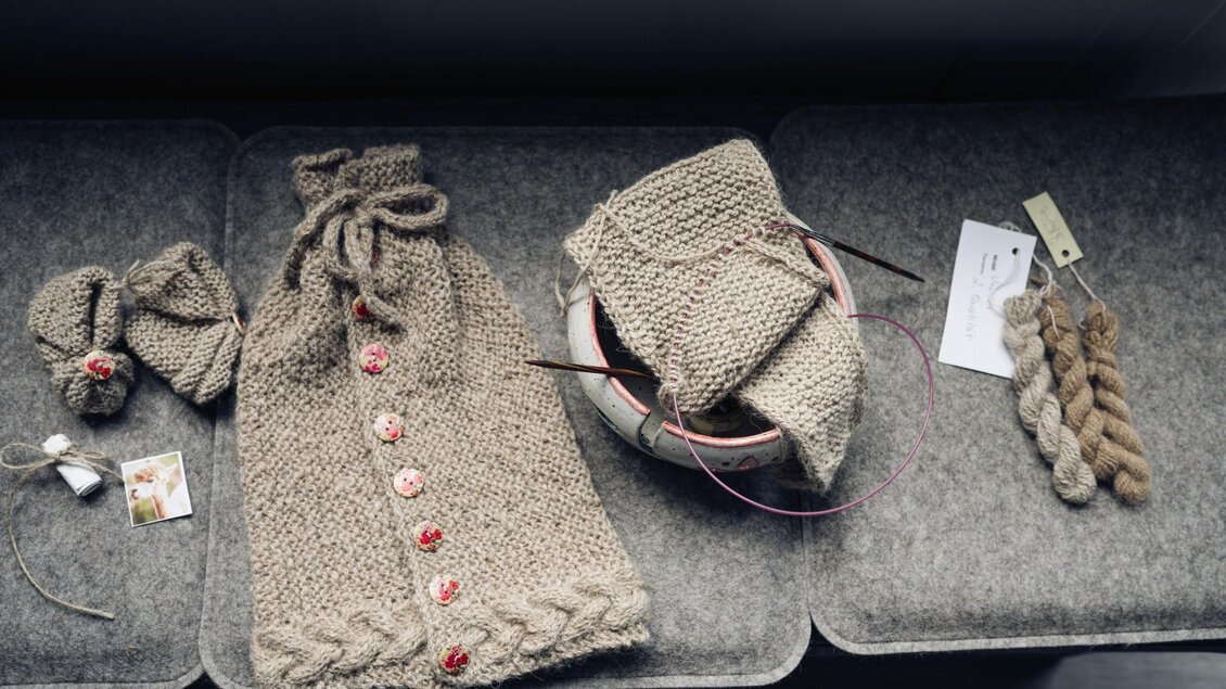 Handgestrickte Kleidungsstücke und Garn aus Alpakawolle liegen auf einer Ablage. | © Bernd Grosseck