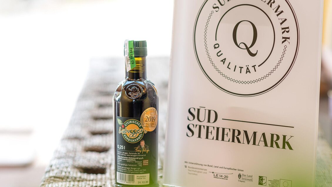 Eine Flasche Öl steht neben einem Qualitätsschild für die Region Südsteiermark. Die Präsentation zeigt hochwertige lokale Produkte. | © RM SWS GmbH | webquartier.at