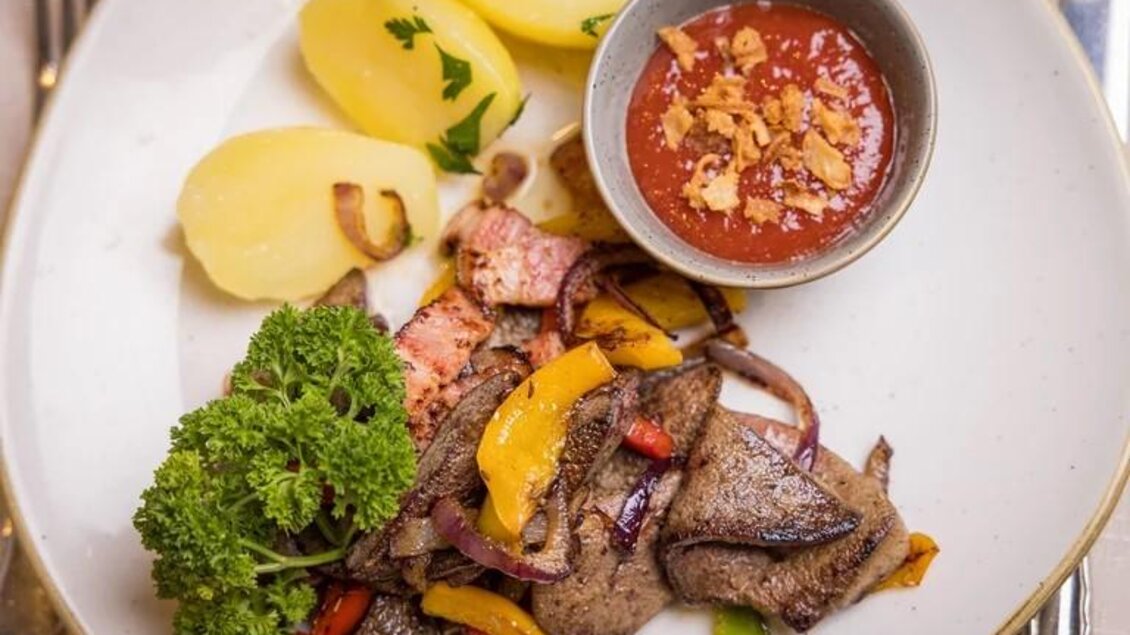 Ein Teller mit zartem Fleisch, buntem Gemüse und gekochten Kartoffeln. Dazu gibt es eine kleine Schüssel mit einer würzigen Sauce. | © Wild und Team Fotoagentur GmbH