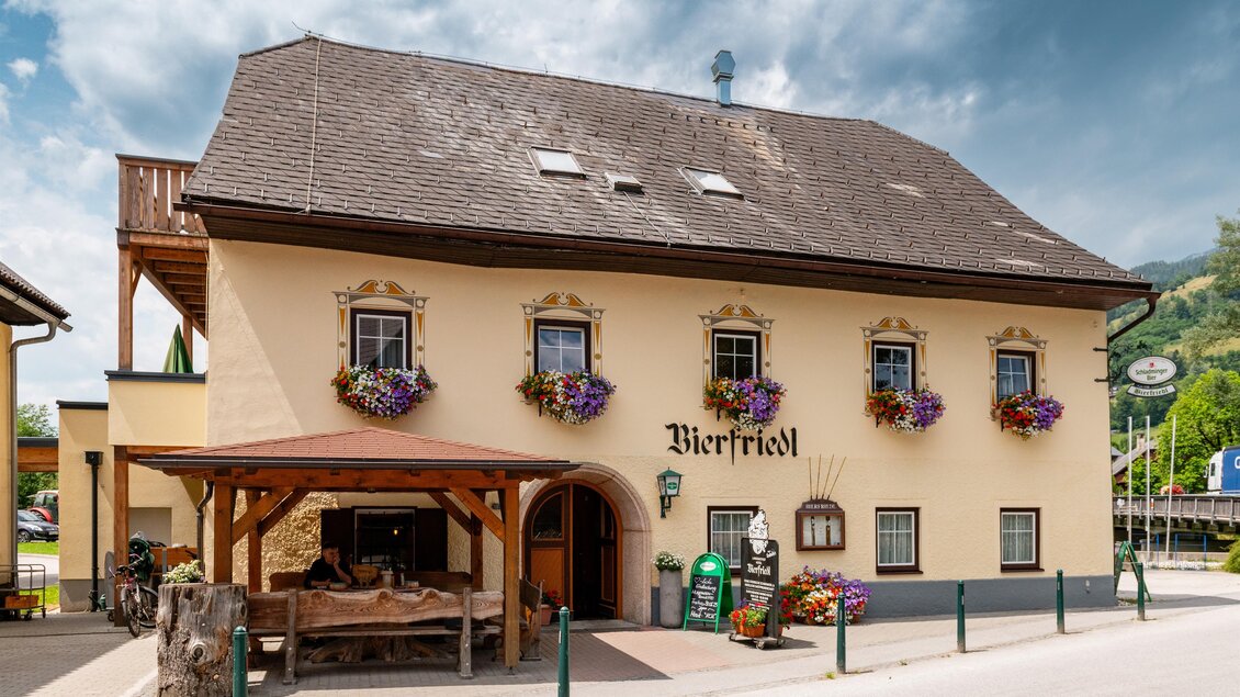 Ein traditionelles Gasthaus mit dem Namen "Bierhimmel". Die Fassade ist mit Blumen dekoriert und der Himmel ist bewölkt.