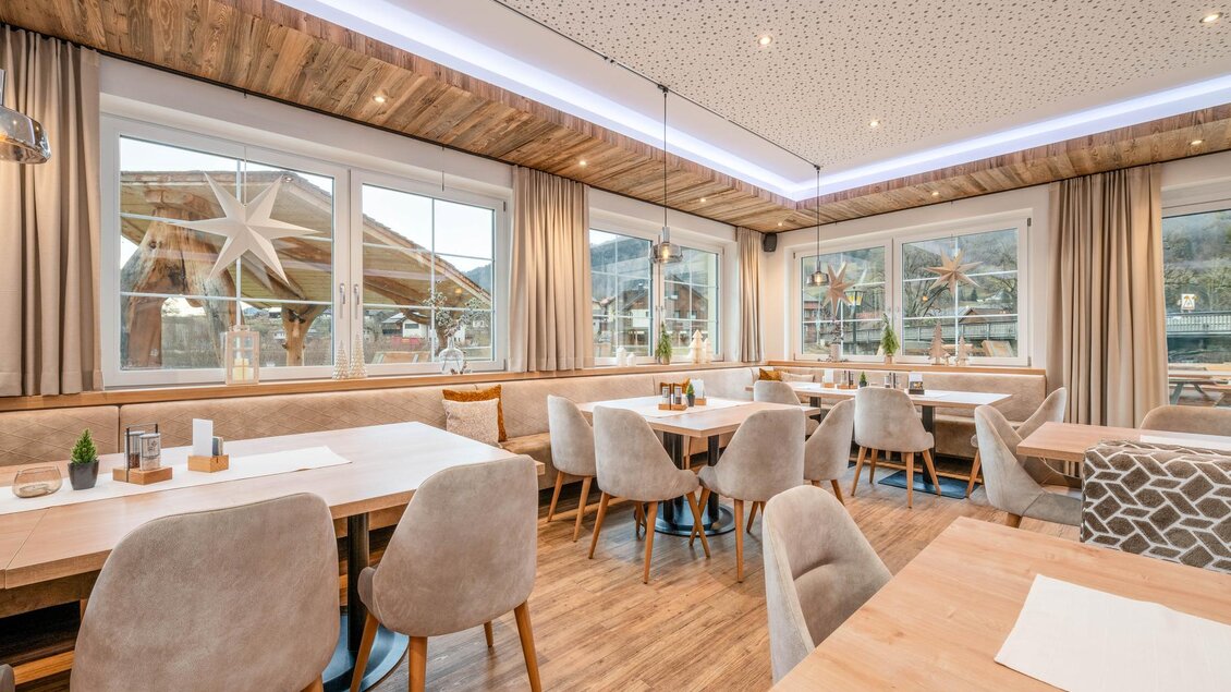 Ein modernes Restaurant mit gemütlichen Tischen und Stühlen. Große Fenster sorgen für viel Tageslicht und Blick auf die Umgebung.