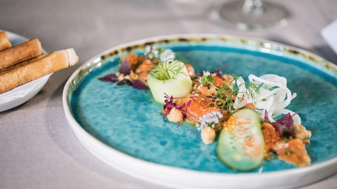 Farbenfroh angerichtetes Gericht mit Gemüse, Kräutern und essbaren Blüten auf einem blauen Teller im Landhof Lazarus in Mooskirchen | © LazarusSoulbrand