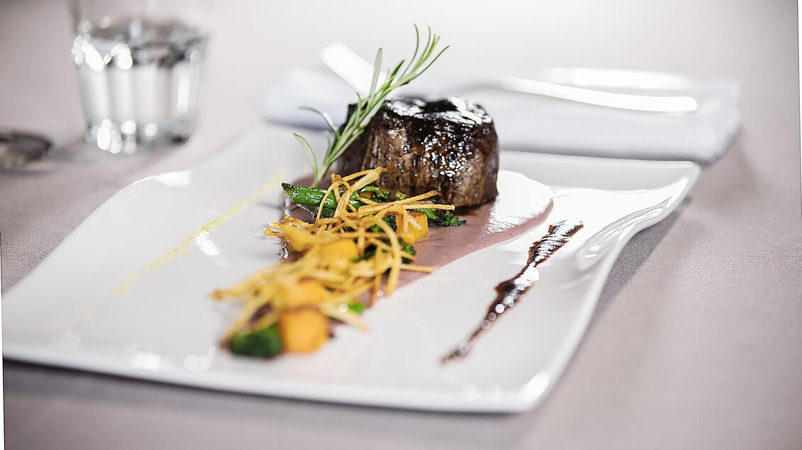 Angerichtetes Fleischgericht mit Gemüse, Kräutern und Sauce auf einem weißen Teller im Landhof Lazarus in Mooskirchen | © LazarusSoulbrand