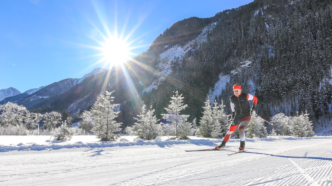 Ein Langläufer fährt durch eine verschneite Landschaft. Die Sonne scheint hell über den schneebedeckten Bergen. | © Gerhard Pilz/Tourismusverband Schladming - Martin Huber