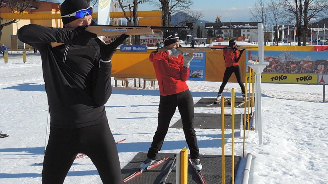 Drei Sportler üben im Schnee mit Skiausrüstung. Sie skaten und zielen mit ihren Gewehren auf die Zielscheiben. | © Herbert Raffalt