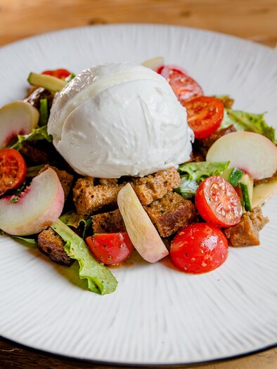A freshly prepared dish with salad, cherry tomatoes, and toasted bread. Topped with a poached egg. | © Region Graz - Mias Photoart